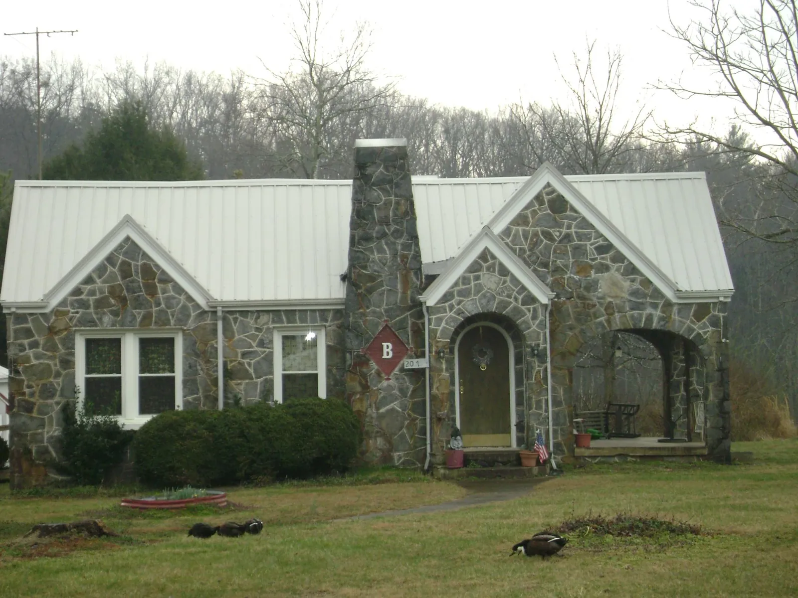 White metal roof on a stone cottage with steep gables in Madison